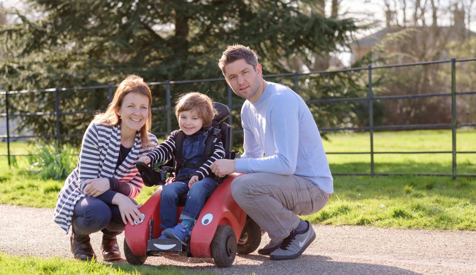 Little boy in his Wizzybug with his mum and dad in the park