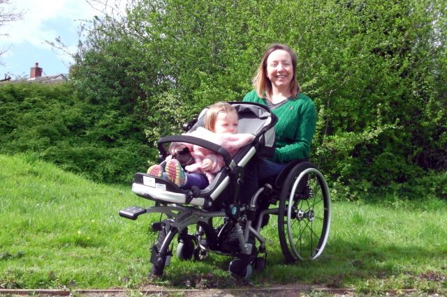 A mother using her wheelchair with her daughter in the wheelchair baby carrier
