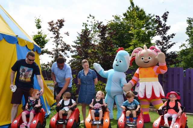 Five children in Wizzybug powered wheelchairs posing with characters at CBeebies Land