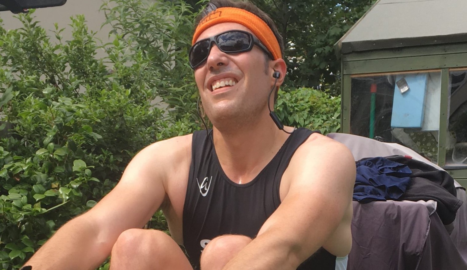 Person on rowing machine, wearing sunglasses and orange sweatband on head